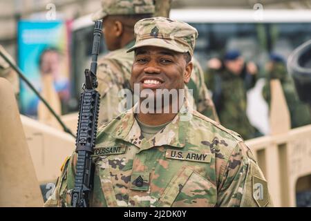 Soldat souriant du corps des Marines des États-Unis avec des lunettes de soleil, un fusil de chasse et un véhicule blindé humvee en arrière-plan pendant la guerre, les troupes des États-Unis ou de l'armée américaine Banque D'Images