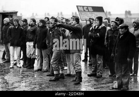 La grève nationale des mineurs 1985 alors que Dawn brise les mineurs traversent la cour de la mine de charbon Ashington pour retourner au travail le 20 janvier 1985, des piquets de grève en colère et contrariés crient aux travailleurs qui retournent à l'intérieur de la mine de charbon Banque D'Images