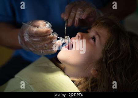 Mignon garçon assis à la chaise dentaire avec la bouche ouverte pendant la vérification orale avec le médecin. Cabinet de dentiste en visite. Stomatologie pour enfants. Cavité orale pour enfants. Banque D'Images