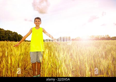 Un jeune garçon se lève les mains dans le champ de blé Banque D'Images