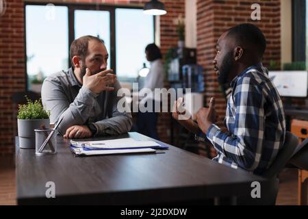 Jeune recruteur d'entreprise pour adultes expliquant la politique de travail du candidat à l'emploi. Le directeur général s'entretient avec un homme confiant tout en examinant le CV et en posant des questions sur l'expérience de travail sur le terrain Banque D'Images