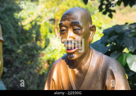Magnifique statue de bouddha photo unique de près. Sculpture dorée représentant un vieux bouddhiste/moine. Chemin principal/allée, dix mille Monastère de Bouddhas. Banque D'Images