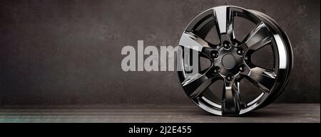 Roue en alliage noir pour voiture SUV sur fond texturé, espace de copie. Banque D'Images