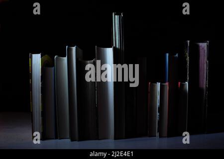 Rangée de livres à dossier rigide sur table en bois sur fond sombre. Retour à l'école,éducation,lecture,recherche. Banque D'Images