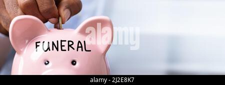 Personne d'économiser de l'argent pour les funérailles en insérant une pièce de monnaie pour Tirelire avec texte funéraire Banque D'Images