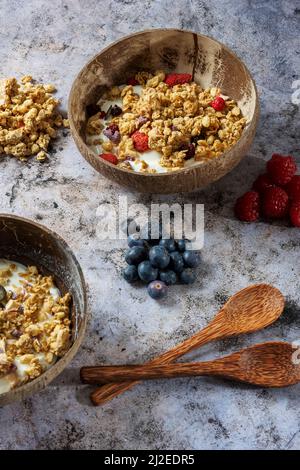 Granola saine avec fruits secs et noix sur un bol de yaourt. Bol en bambou avec des cuillères en bambou Banque D'Images