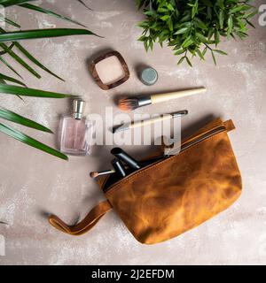 sac de maquillage en cuir brun fait main avec fournitures de maquillage sur une table Banque D'Images