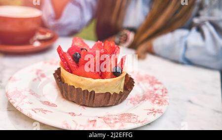 Jeune femme qui goûte un gâteau à la fraise, foyer sélectif. Banque D'Images