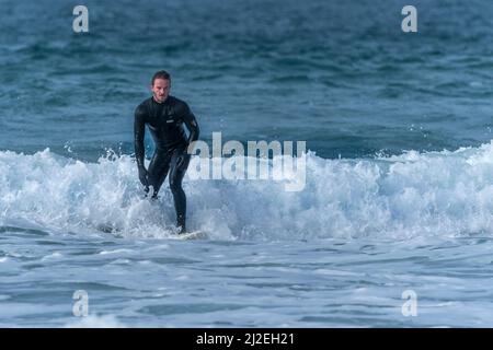 Un surfeur qui profite de l'hiver en surfant à Fistral à Newquay, en Cornouailles, au Royaume-Uni. Banque D'Images