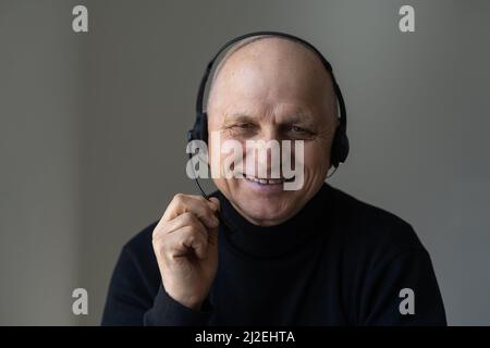 Joyeux 60s ans dans un casque avec micro regardant la caméra commencer la conversation en ligne d'appel vidéo, communiquant avec vos amis ou Banque D'Images