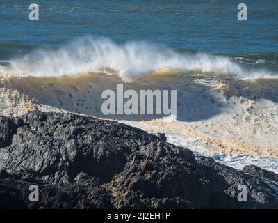 Vagues de l'océan qui se roulent et se brisent au-dessus des rochers, sales et gelées après de fortes pluies et des inondations, projections de jets de mer au-dessus, côte de Nouvelle-Galles du Sud Australie Banque D'Images