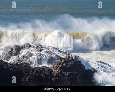 Vagues de l'océan qui se roulent et se brisent au-dessus des rochers, sales et gelées après de fortes pluies et des inondations, projections de jets de mer au-dessus, côte de Nouvelle-Galles du Sud Australie Banque D'Images