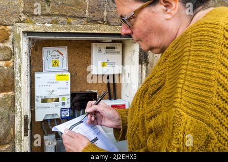 Femme lisant ou vérifiant un compteur d'électricité avec une facture d'électricité. Banque D'Images