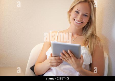 Le est le meilleur gadget jamais vu : la tablette numérique. Jeune femme attrayante utilisant sa tablette avec un sourire. Banque D'Images