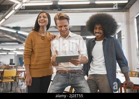 La relation de travail a été excellente. Photo rognée de trois jeunes hommes d'affaires regardant une tablette dans leur bureau. Banque D'Images