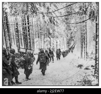 Bataille des Ardennes WW2 hiver neige des troupes d'infanterie américaines des soldats du 289th Infantry Regiment marchent le long de la route enneigée hivernale sur leur chemin pour couper la route Saint Vith-Houffalize en Belgique. Ministère de la Défense. Département de l'armée. Bureau du Chief signal Officer. Des soldats américains du 289th Infantry Regiment marchent le long de la route enneigée en route pour couper la route Saint Vith-Houffalize en Belgique. Date 24 janvier 1945 ils avançaient pour bloquer l'armée allemande nazie en retraite. Banque D'Images