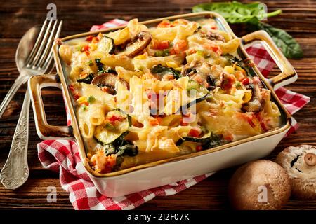 La meilleure dose de penne cuite au four avec des champignons et des courgettes servies dans une casserole sur un comptoir en bois pour le déjeuner Banque D'Images