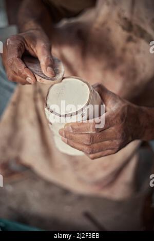 l'artiste lustrant les bords rugueux d'une casserole avec une éponge dans un studio de poterie. Banque D'Images