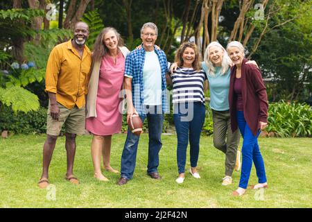 Portrait d'amis multiraciaux senior souriants, hommes et femmes, avec des bras autour de jouer au rugby Banque D'Images