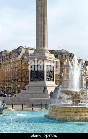 Un homme seul assis sur le socle de Nelsons Column à l'aide d'un téléphone portable Trafalgar Square, centre de Londres, Angleterre, Royaume-Uni Banque D'Images