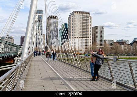 Un jeune couple de touristes prenant un selfie sur le pont piétonnier Golden Jubilee au-dessus de la Tamise, Charing Cross centre de Londres Angleterre Banque D'Images