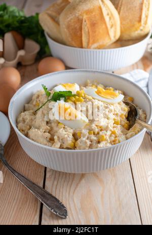 Salade de thon avec mayonnaise, œufs durs, oignons et maïs dans un bol avec une cuillère. Banque D'Images