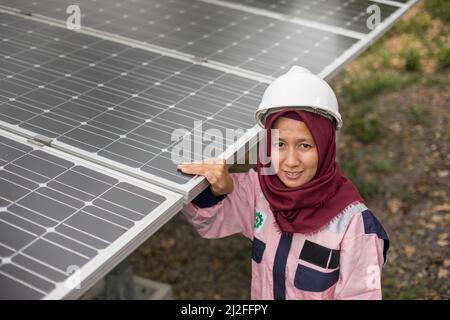 Un technicien électrique junior, Verawati (23), inspecte et entretient des panneaux solaires sur l'île de Karampuang, en Indonésie, qui ont été installés dans le cadre du Banque D'Images