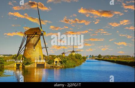 Vue sur le canal d'eau néerlandais sur les anciens moulins à vent, prairie verte dans la campagne rurale pendant le coucher du soleil - Kinderdijk, pays-Bas Banque D'Images