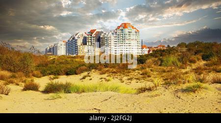 Vue sur les dunes de sable avec de l'herbe sur les bâtiments belges modernes de la ville côtière contre l'automne spectaculaire ciel nuageux - Knokke -Heist, Belgique Banque D'Images