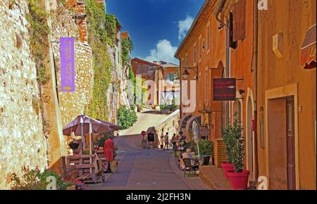 Roussillon en Provence, France - octobre 2. 2019: Vue sur la rue avec mur de pierre naturelle de la forteresse et des maisons jaunes ocre méditerranéennes contre blu Banque D'Images