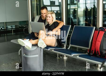 Concept de déplacement. En attente de l'embarquement. Couple amoureux heureux en tenue décontractée dans le terminal de l'aéroport avec passeport avec des billets. Banque D'Images