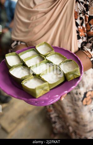 Une femme présente des gâteaux de riz doux fraîchement préparés enveloppés de feuilles de banane sur l'île de Karampuang, Sulawesi Ouest, Indonésie, Asie. Banque D'Images