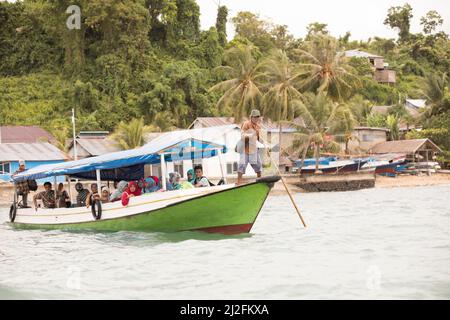 Les bateaux-ferries à passagers poussent dans l'eau, guidés par un plaisantant avec un personnel d'un petit village de pêcheurs sur l'île de Karampuango, en Indonésie. Banque D'Images