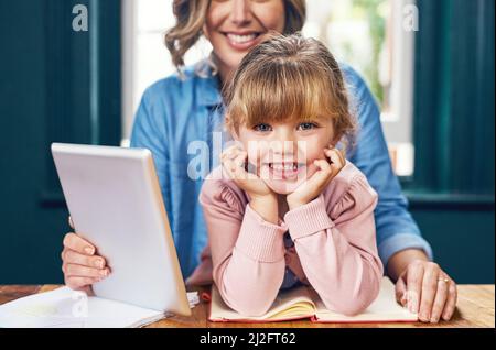 Quel petit chéri. Portrait d'une petite fille gaie assise avec son visage reposant sur ses mains tout en regardant l'appareil photo. Banque D'Images