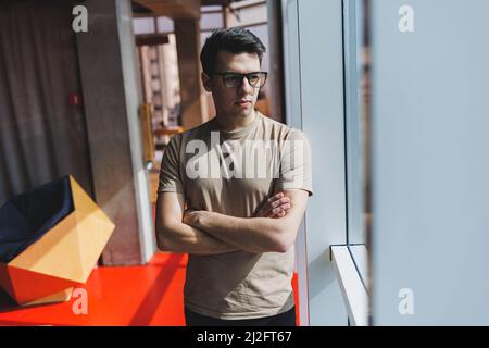 Homme d'affaires réussi dans le bureau debout près de la fenêtre pendant une journée de travail dans l'entreprise, un patron d'entreprise réussi se sent bon d'un Banque D'Images