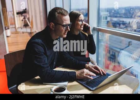 Une équipe d'affaires réussie, des collègues hommes et femmes qui parlent au travail, discutent d'un nouveau projet avec un ordinateur portable, les jeunes cadres ont des convers amicaux Banque D'Images