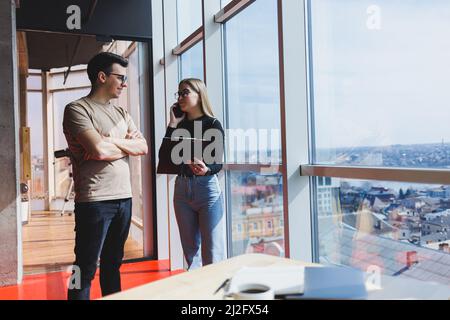 Une jeune femme d'affaires avec des documents en lunettes se tient avec un Manager tout en tenant une réunion d'affaires dans un bureau moderne. Affaires moi Banque D'Images