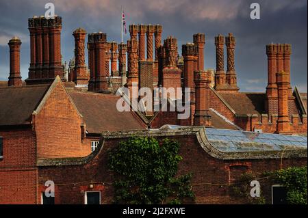 Des cheminées Tudor ornées de briques rouges s'élèvent au-dessus des toits du palais de Hampton court dans le quartier londonien de Richmond-upon-Thames, en Angleterre. Le palais a été construit au début des années 1500 par le cardinal Thomas Wolsey (1473 - 1530) mais a été saisi par le roi Henri VIII (1491 - 1547). Il y a plus de 240 cheminées en tout, sans deux modèles exactement identiques. Banque D'Images