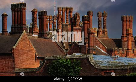 Cheminées Tudor en briques rouges élaborées - pas deux tout à fait semblables - vues dans un ciel orageux au-dessus du palais de Hampton court, près de la Tamise dans le quartier londonien de Richmond-upon-Thames, Angleterre, Royaume-Uni. Le palais, construit à partir de 1515 par le cardinal Thomas Wolsey, possède la plus grande collection de cheminées d'Angleterre - 241 en tout. Après que Wolsey est tombé en disgrâce en 1529, les immenses chambres et appartements de Hampton court ont été occupés par le roi Henri VIII et plus de 1 000 courtisans. Banque D'Images