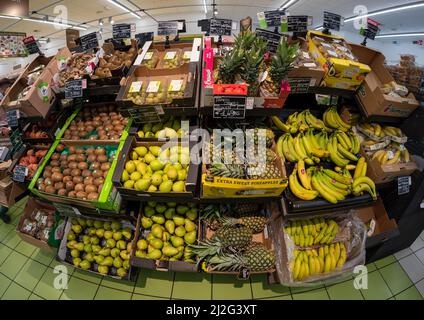 Fossano, Italie - 30 mars 2022: Stand vendant des fruits avec des caisses colorées à l'ananas, aux poires, aux bananes et aux kiwy dans un supermarché italien. Banque D'Images