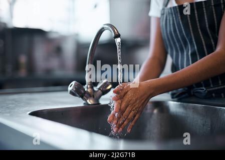 La bonne nourriture commence par une bonne hygiène. Coupe courte d'une femme se lavant les mains dans l'évier d'une cuisine commerciale. Banque D'Images