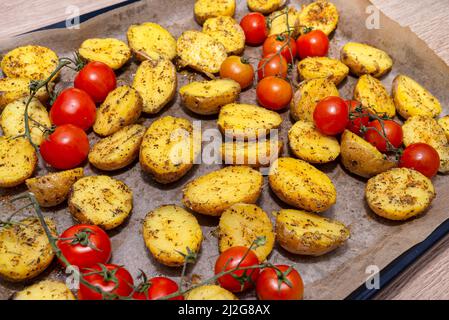 Pommes de terre bouillies et tomates cerises crues préparées pour la cuisson sur un plateau, allongé sur la table. Banque D'Images