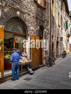 Une belle photo d'une rue au sol en pierre avec des boutiques de souvenirs dans le centre historique de Gubbio, région de l'Ombrie, Italie Banque D'Images