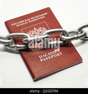 Chaîne métallique sur le passeport russe avec couverture rouge sur fond blanc. Sanctions et concept de rideau de fer. Banque D'Images