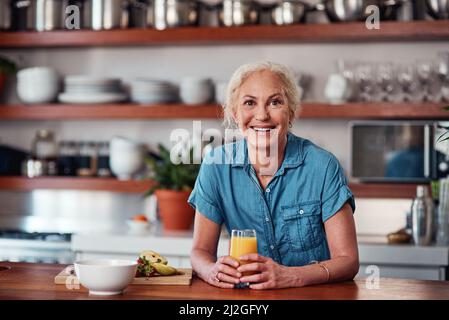 Je commence toujours ma journée avec un verre de jus d'orange. Portrait court d'une femme âgée attrayante en train de savourer un verre de jus d'orange pendant la préparation Banque D'Images