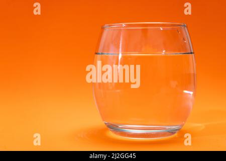 Gobelet en verre avec eau purifiée sur fond de dégradé orange. Copier l'espace Banque D'Images