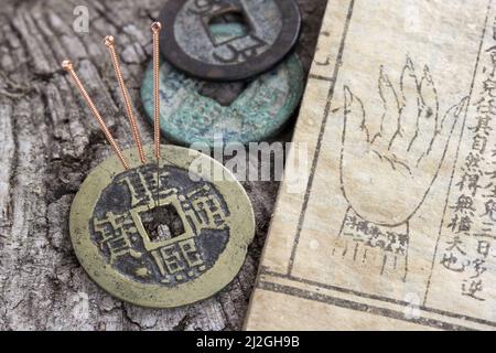 aiguilles d'acupuncture à côté d'un vieux livre de médecine et de pièces anciennes Banque D'Images