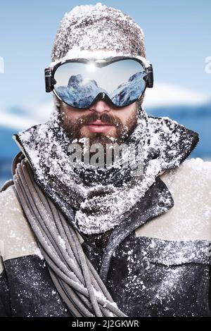 Atteindre le ciel. Portrait d'un alpiniste avec un reflet de sommets enneigés dans son pare-neige. Banque D'Images