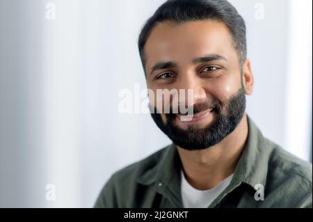 Portrait en gros plan d'un homme d'affaires, d'un responsable ou d'un spécialiste INFORMATIQUE indien ou arabe à barbe positive, portant une chemise décontractée, regardant l'appareil photo avec un sourire amical Banque D'Images