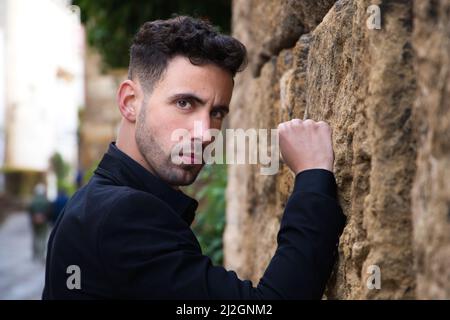 Un gitan dansant le flamenco habillé de noir, pendu avec colère sur un mur avec son poing, Espagne Banque D'Images